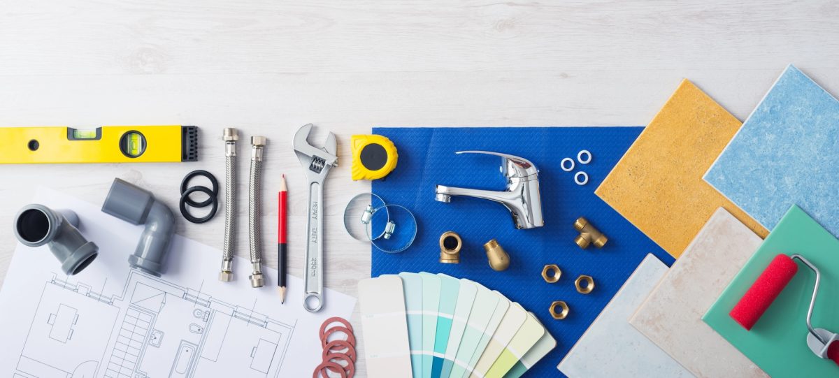 Plumbing fittings, tap, tiles and colour swatches laid out on renovation plans